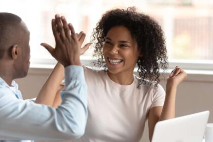 Young black colleagues high-fiving each other at work