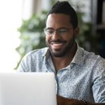 Man smiling and working on laptop