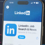 LinkedIn app on a smartphone screen with a background of computer code, highlighting profile enhancement and networking features for in-demand skills.