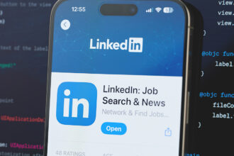 LinkedIn app on a smartphone screen with a background of computer code, highlighting profile enhancement and networking features for in-demand skills.