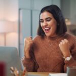 Young brown woman delighted with what she sees on her screen