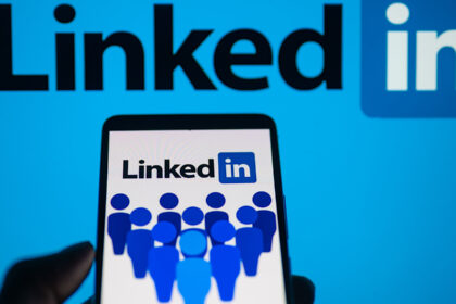 LinkedIn logo displayed on a smartphone with LinkedIn on screen seen in the background, in this photo illustration.