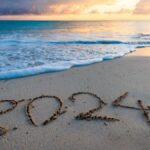 2024 year number handwritten on a sandy beach at sunrise