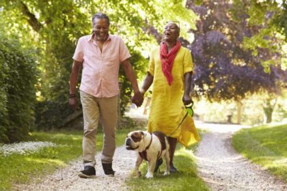 Senior Couple Walking With Pet Bulldog In Countryside