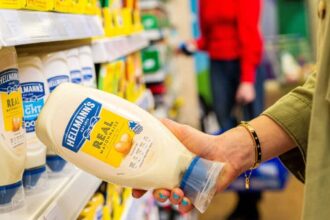 Lady taking a bottle of Hellmann's Real Mayonnaise from a supermarket shelf