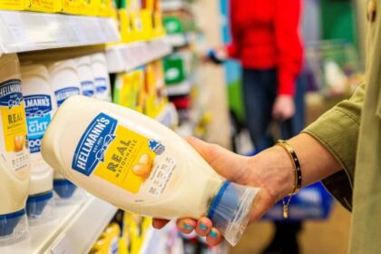 Lady taking a bottle of Hellmann's Real Mayonnaise from a supermarket shelf
