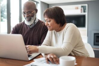happy senior couple using a laptop in their living room to look at their financial budgets