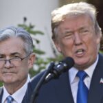 Federal Reserve Chair Jerome Powell standing behind President Donald Trump.